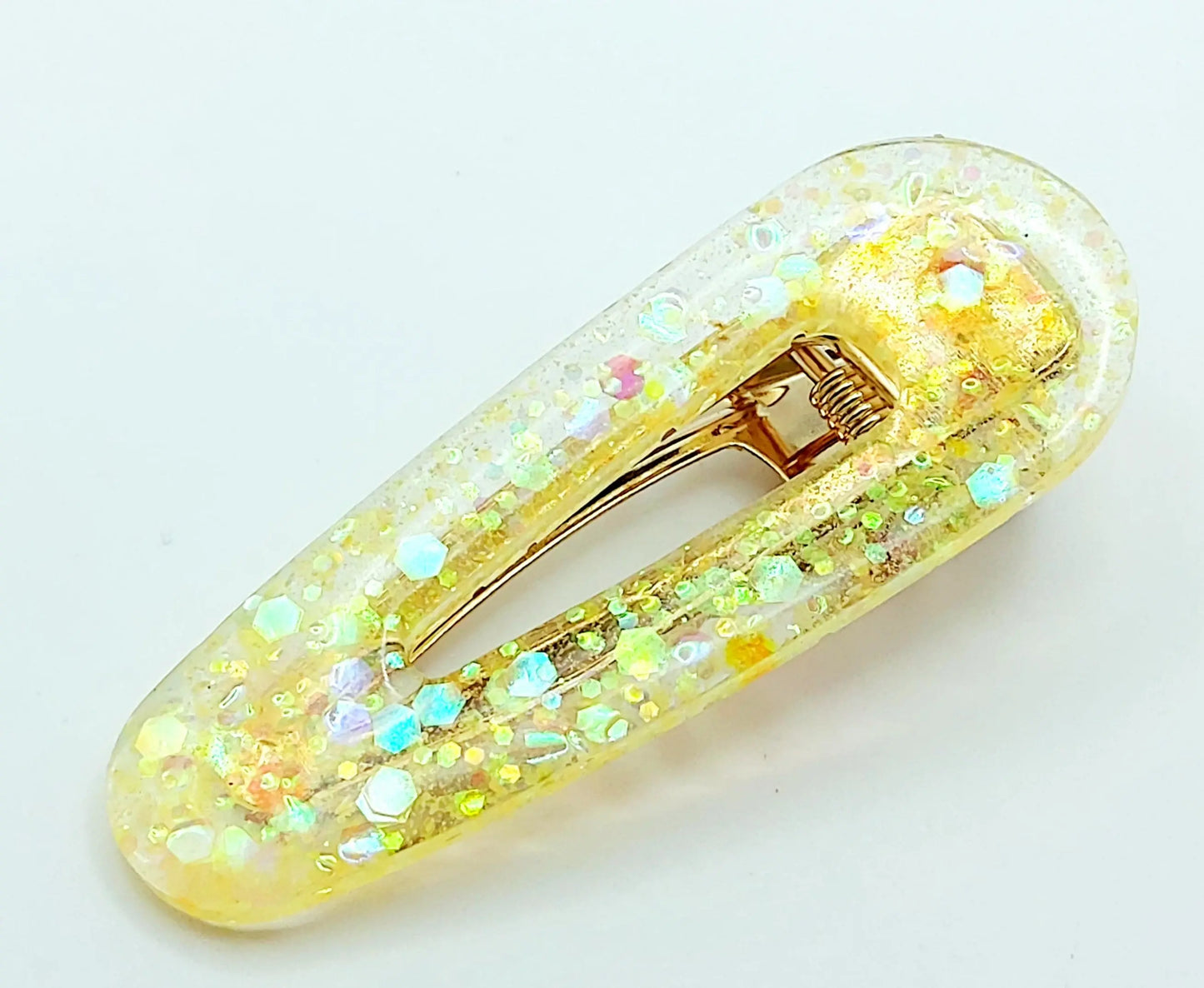 Barrette à cheveux arrondie en résine époxy. Jaune translucide et paillettes holographiques.