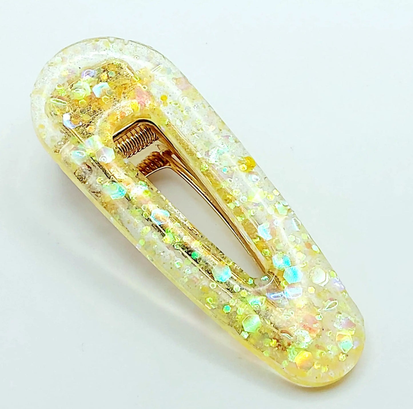 Barrette à cheveux arrondie en résine époxy. Jaune translucide et paillettes holographiques.
