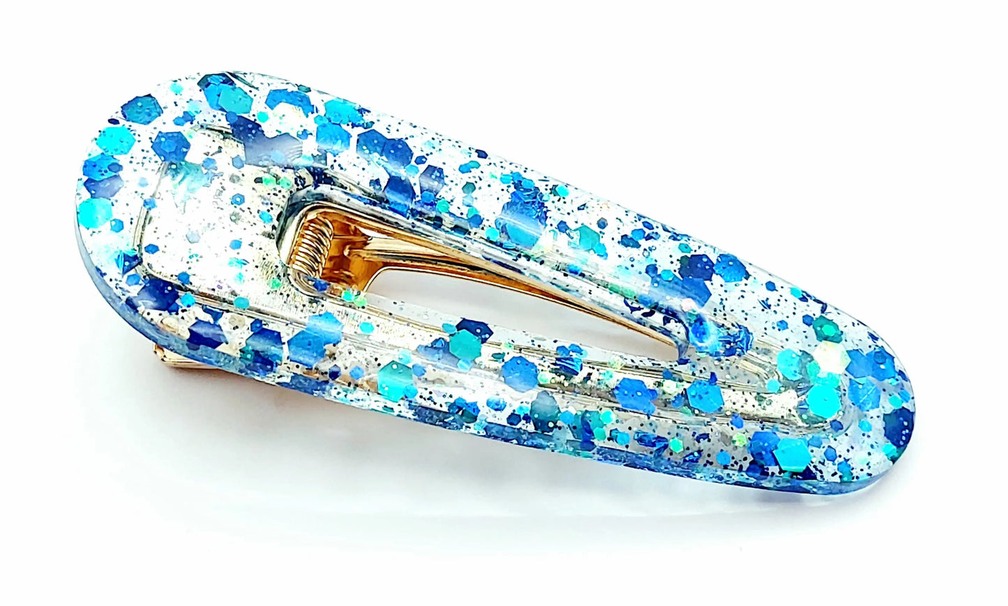 Barrette à cheveux arrondie en résine époxy. Transparente et paillettes bleues. Gros plan.