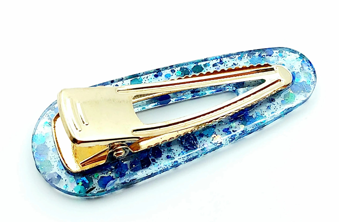 Barrette à cheveux arrondie en résine époxy. Transparente et paillettes bleues. Vue de l'envers.