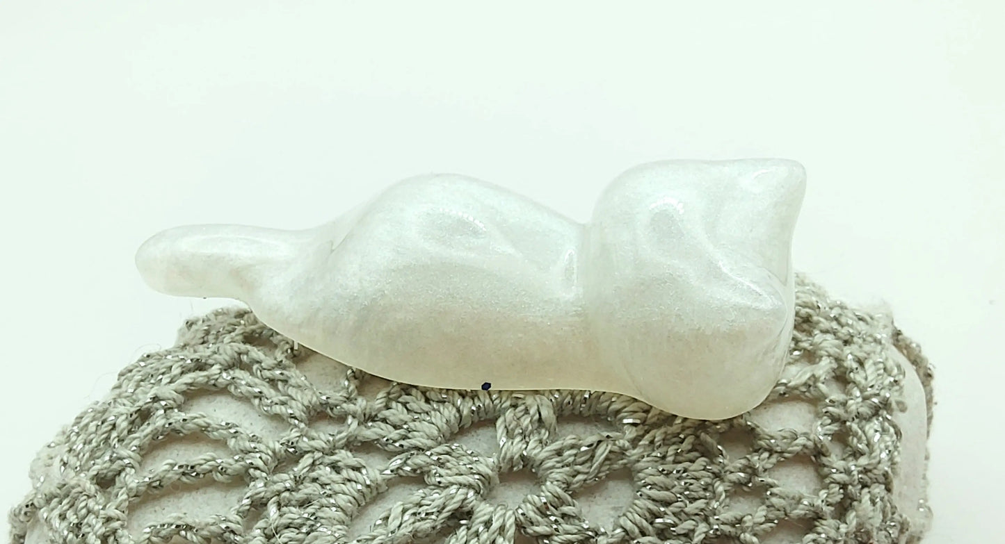 Figurine "Chaton couché" en résine époxy, blanc nacré. Posé sur un galet. Gros plan.