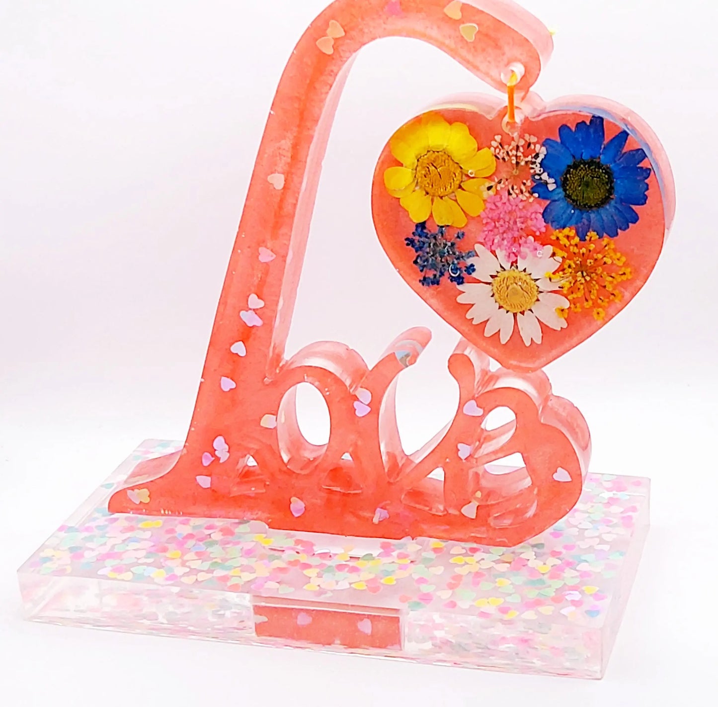 Mot décoratif LOVE sur socle en résine époxy. Rose avec paillettes coeurs holographiques et fleurs multicolores dans le coeur suspendu.