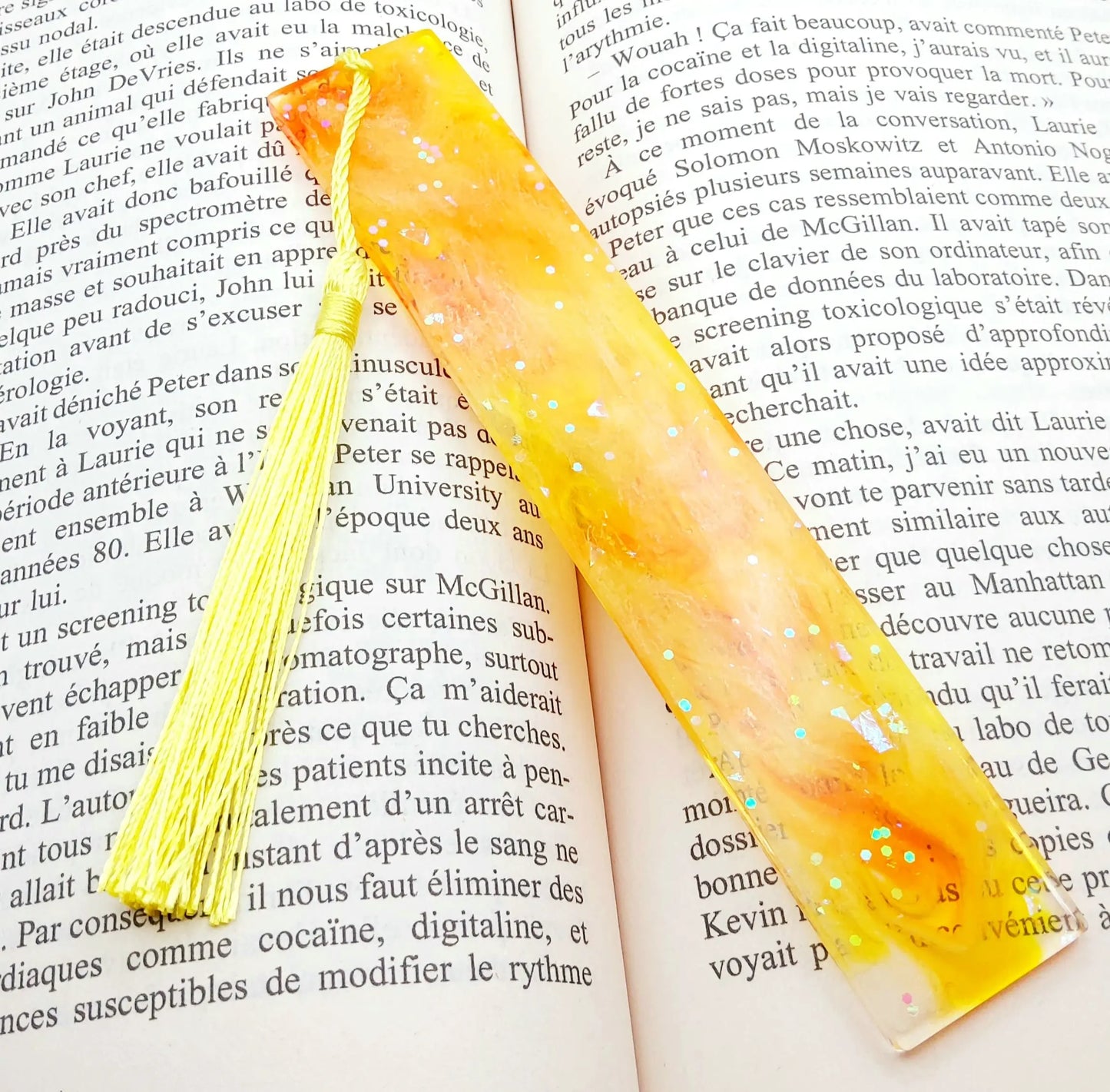 Marque-pages en résine époxy, orange et jaune, posé dans un livre