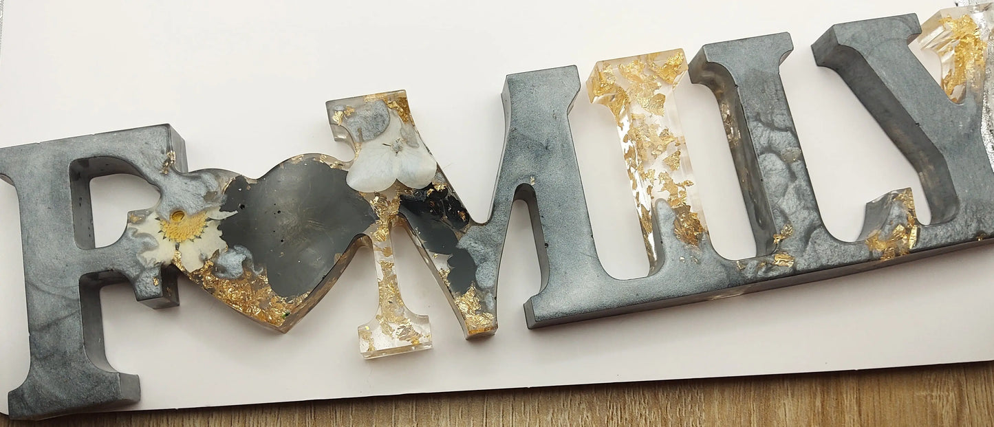 Mot décoratif "FAMILY" en résine époxy. Gris argenté, fleurs noires et blanches. Feuille d'or.