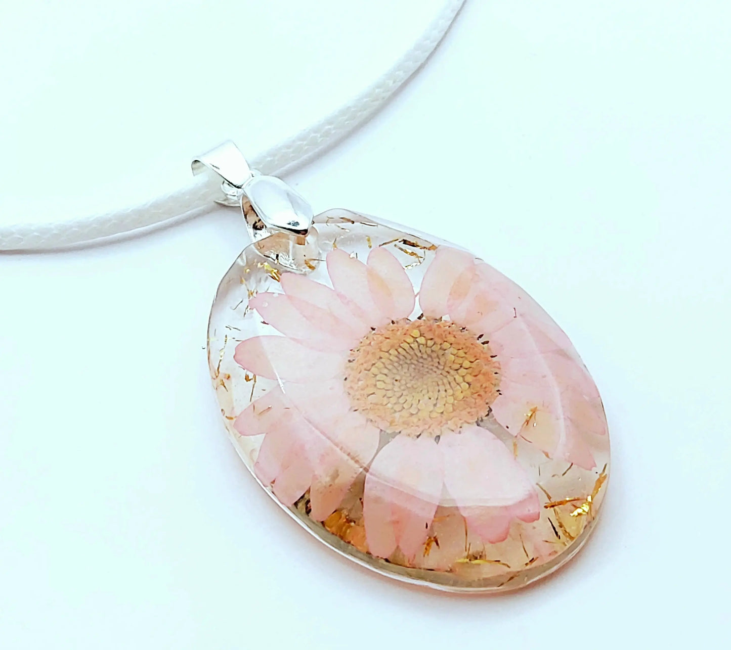 Pendentif OVALE en résine époxy. Fleur rose et paillettes dorées. Cordon en coton ciré blanc. PRETTY RESINE