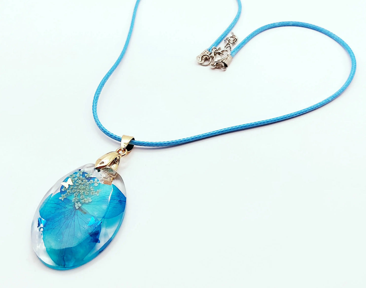 Pendentif OVALE en résine époxy. Fleurs bleue et blanche. Cordon en coton ciré bleu. PRETTY RESINE