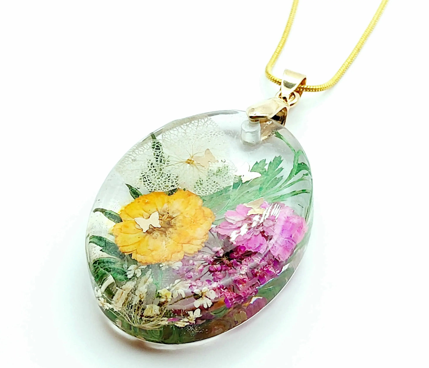 Pendentif Ovale en résine époxy et sa chaîne dorée. Fleurs multicolores et papillons dorés.