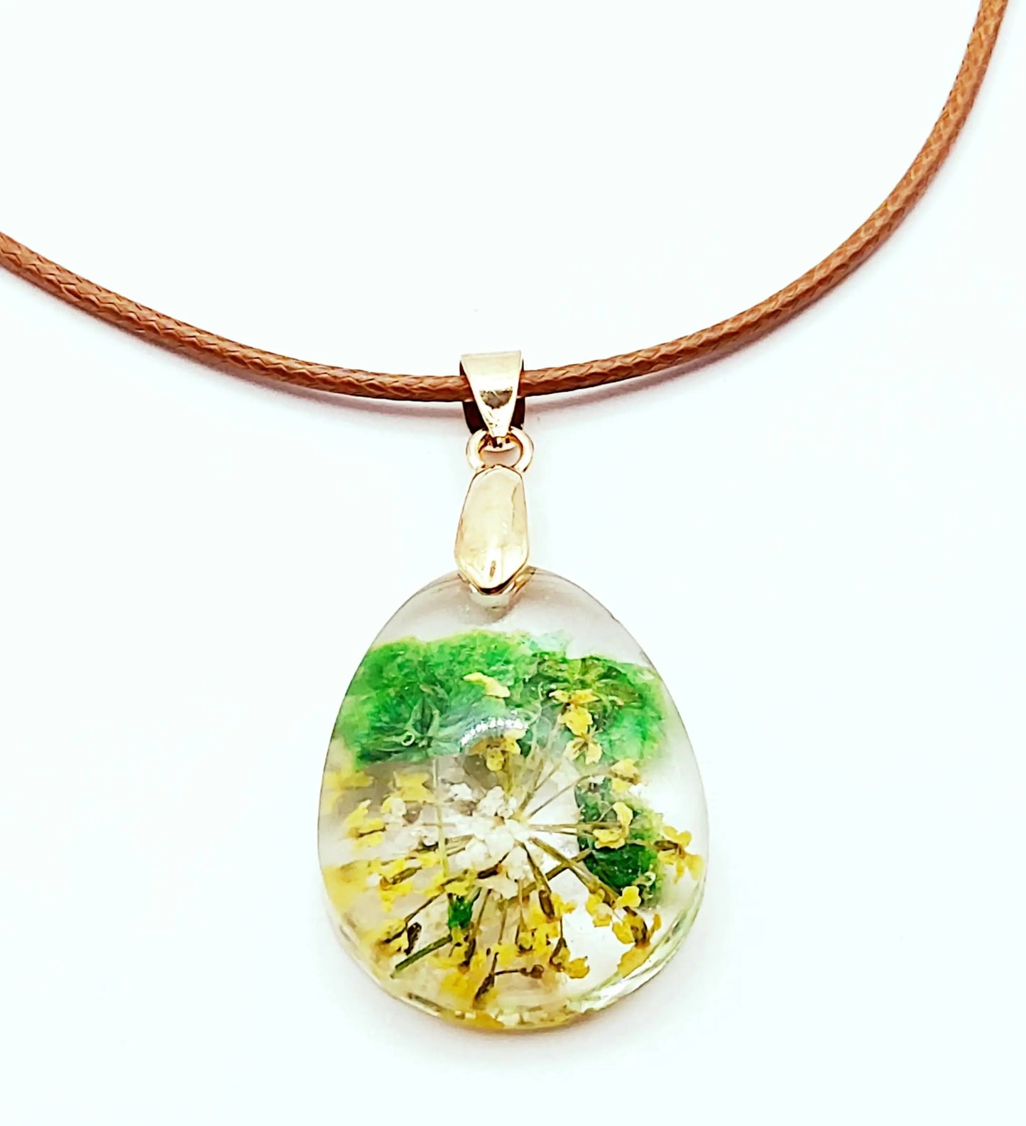 Pendentif "Goutte d'eau" en résine époxy. Fleurs vertes et jaunes. Cordon en coton ciré marron. Gros plan.