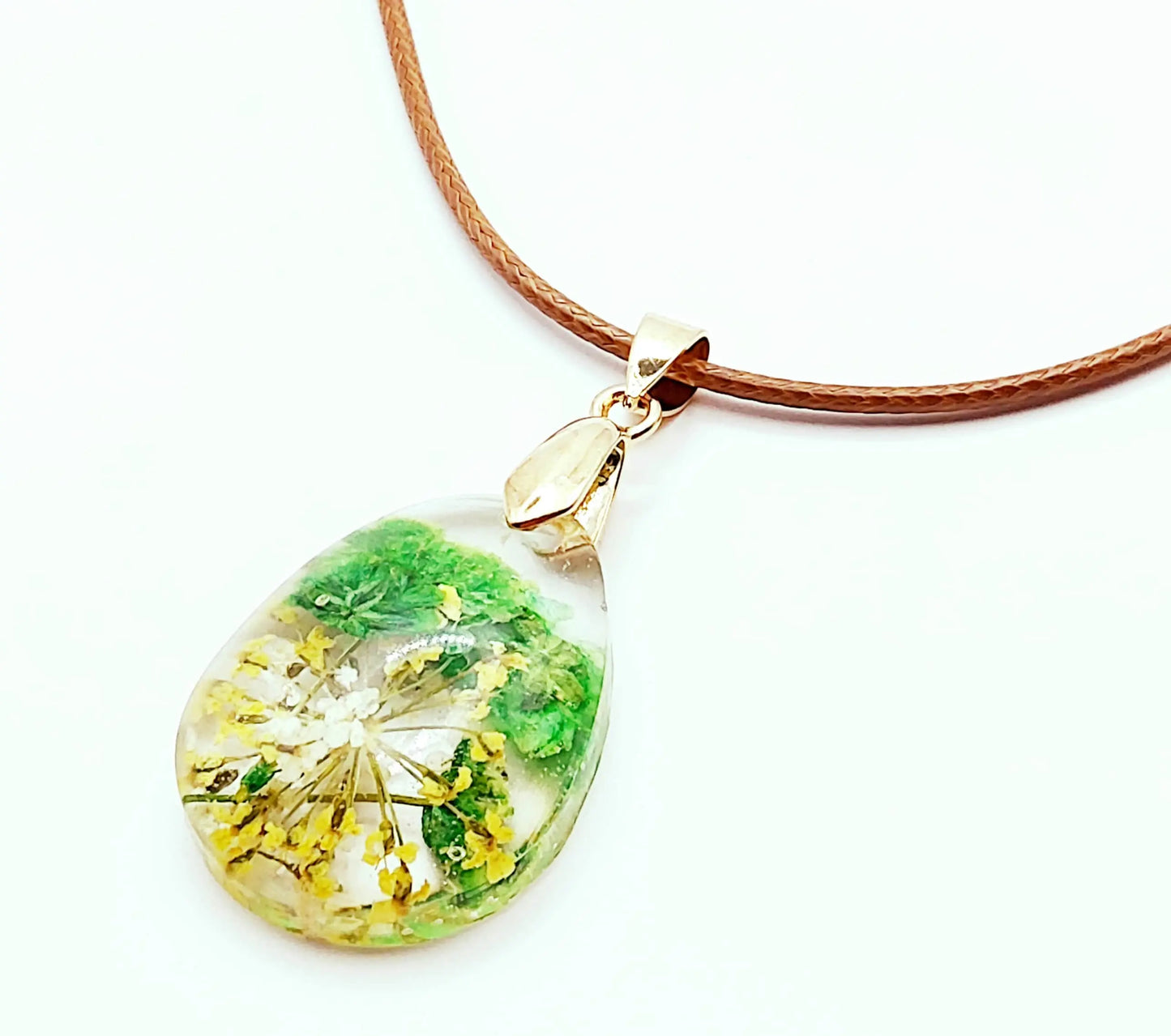 Pendentif "Goutte d'eau" en résine époxy. Fleurs vertes et jaunes. Cordon en coton ciré marron.