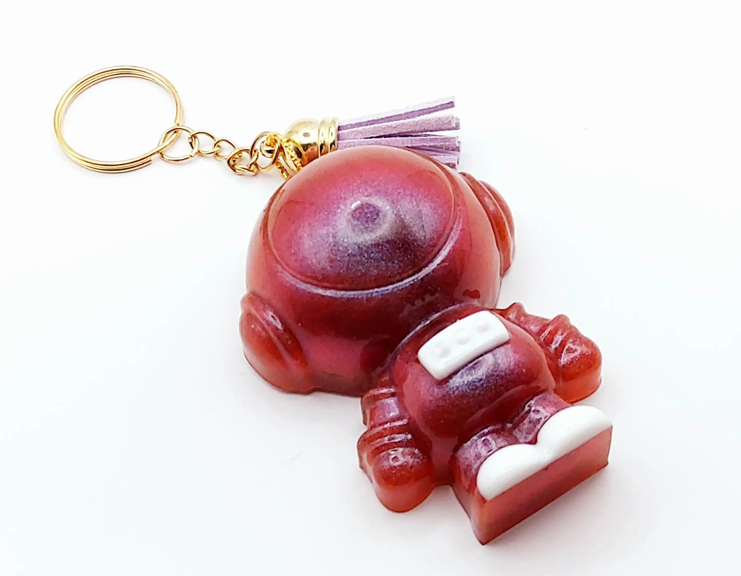 Porte-clés ASTRONAUTE en résine époxy. Mauve, rose irisé. Anneau doré. Pompon gland mauve.