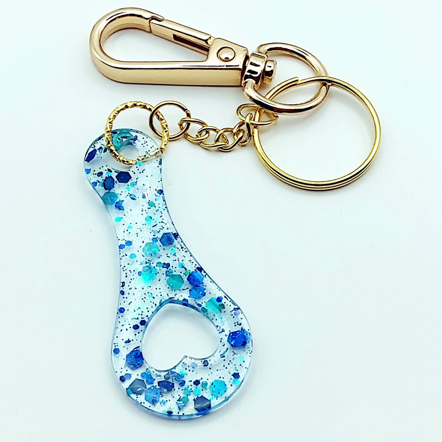 Porte-clés Jeton de caddie en résine époxy, transparent et paillettes bleues. Anneau et mousqueton dorés.