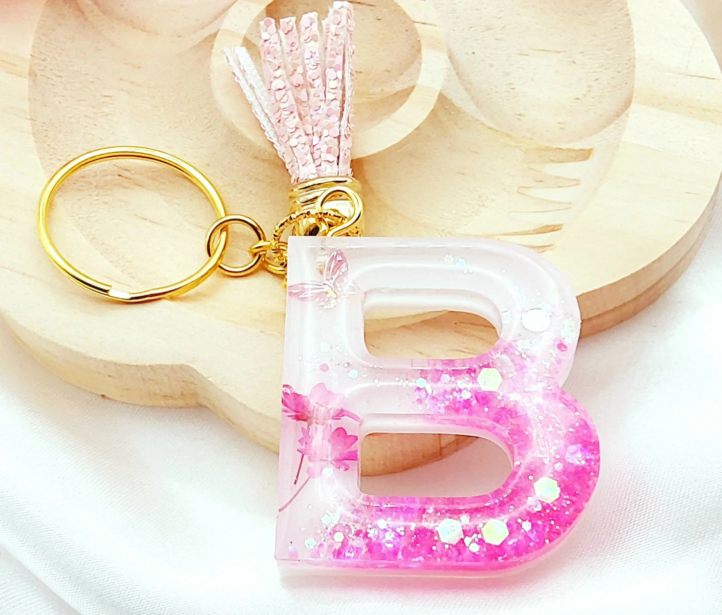 Porte-clés LETTRE B en résine époxy. Fond blanc. Paillettes, fleurs et papillon roses. PRETTY RESINE
