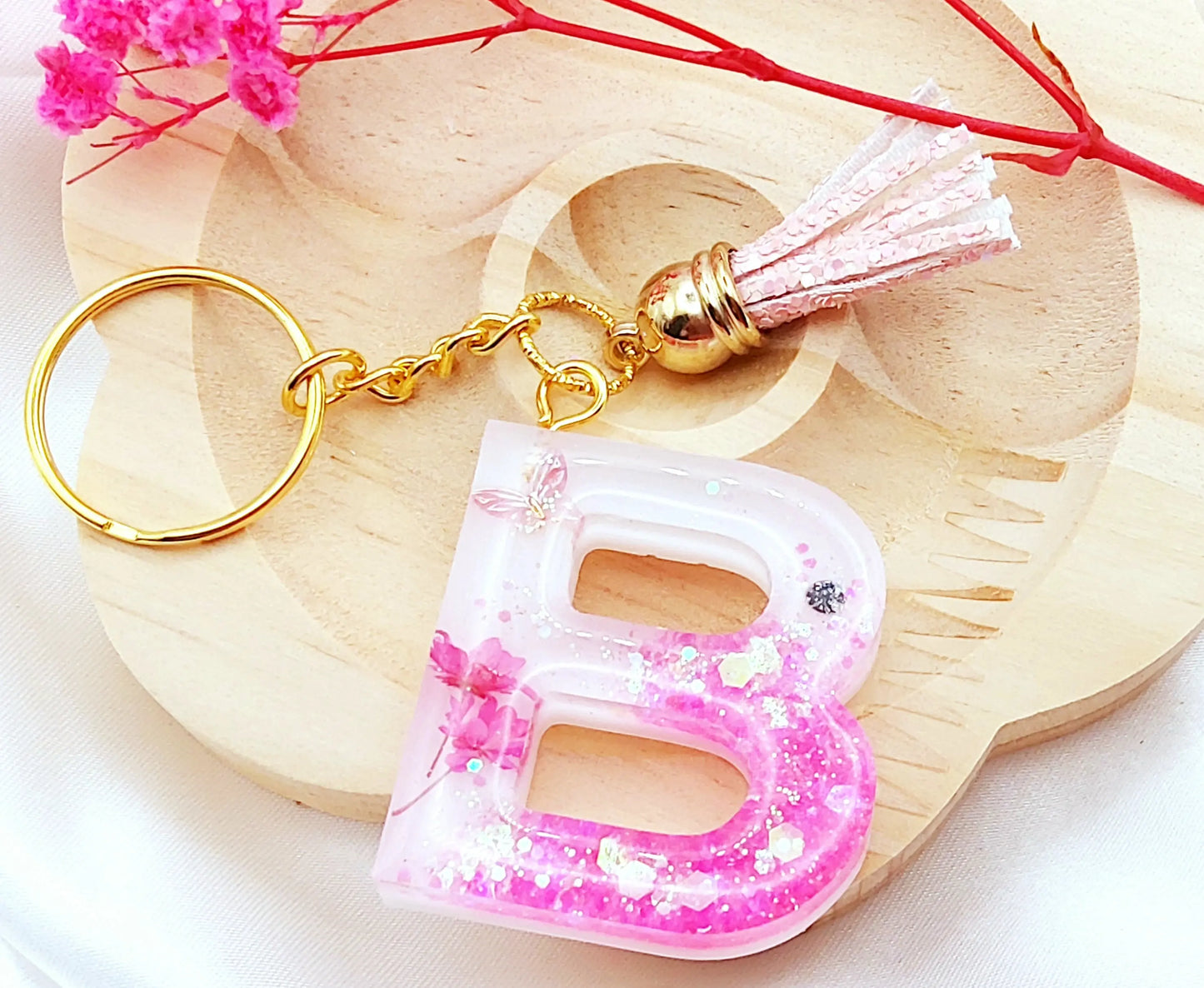 Porte-clés LETTRE B en résine époxy. Fond blanc. Paillettes, fleurs et papillon roses. PRETTY RESINE