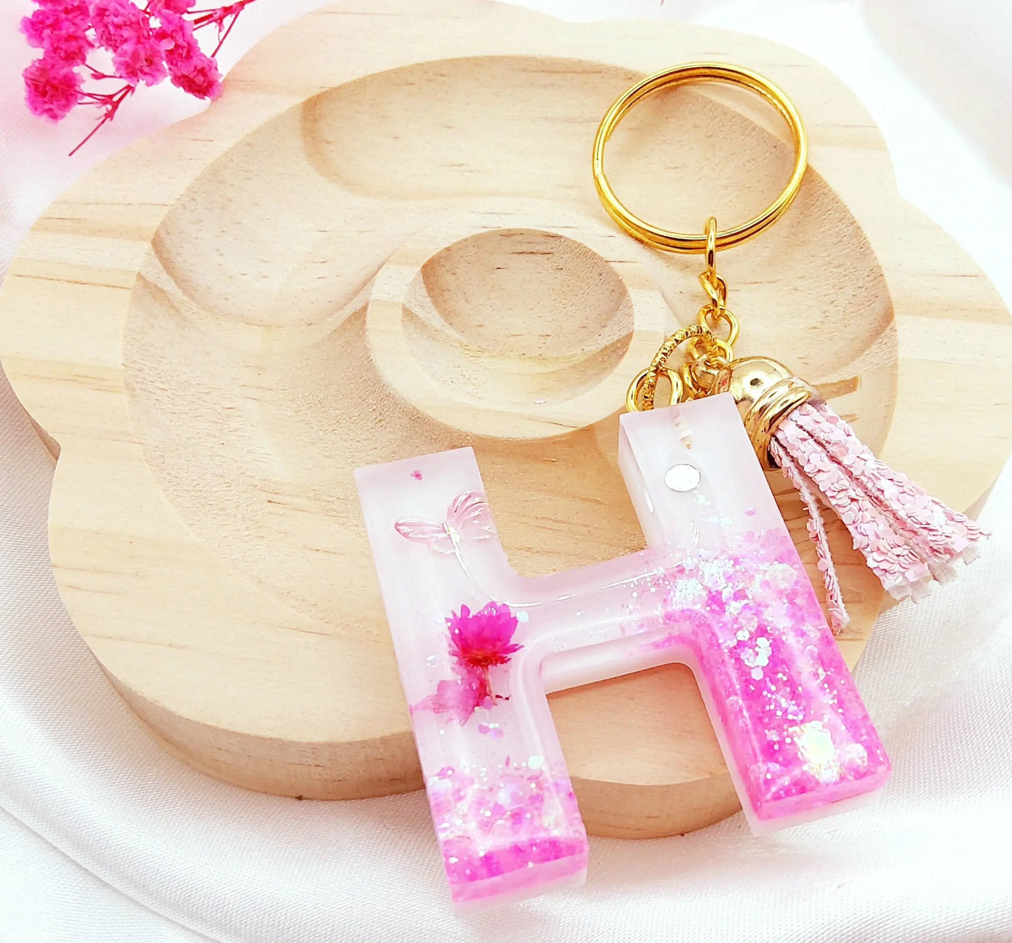Porte-clés LETTRE H en résine époxy. Fond blanc. Paillettes, fleurs et papillon roses. Pompon gland pailleté rose - PRETTY RESINE