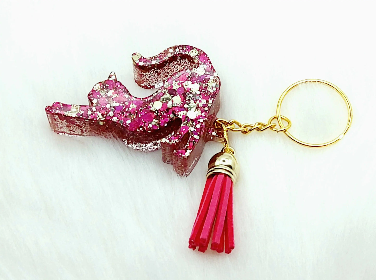 Porte-clés CHAT QUI S'ETIRE en résine. Paillettes roses et or. Pompon gland fuchsia.