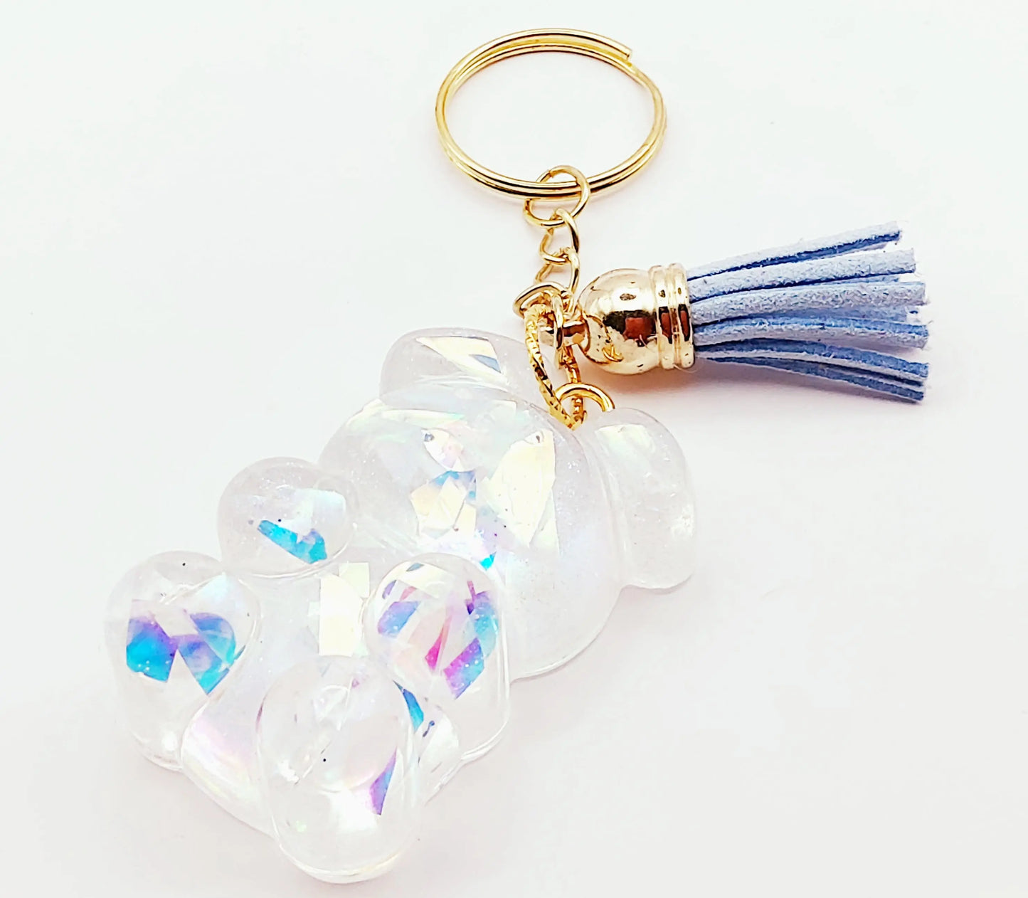 Porte-clés "Ourson debout" en résine époxy. Transparent et holographique. Anneau doré, pompon gland bleu clair.