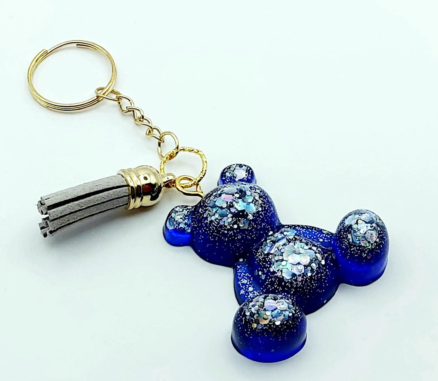 Porte-clés "Ourson assis" en résine époxy, bleu marine et paillettes argentées. Anneau doré. Pompon gland gris clair.