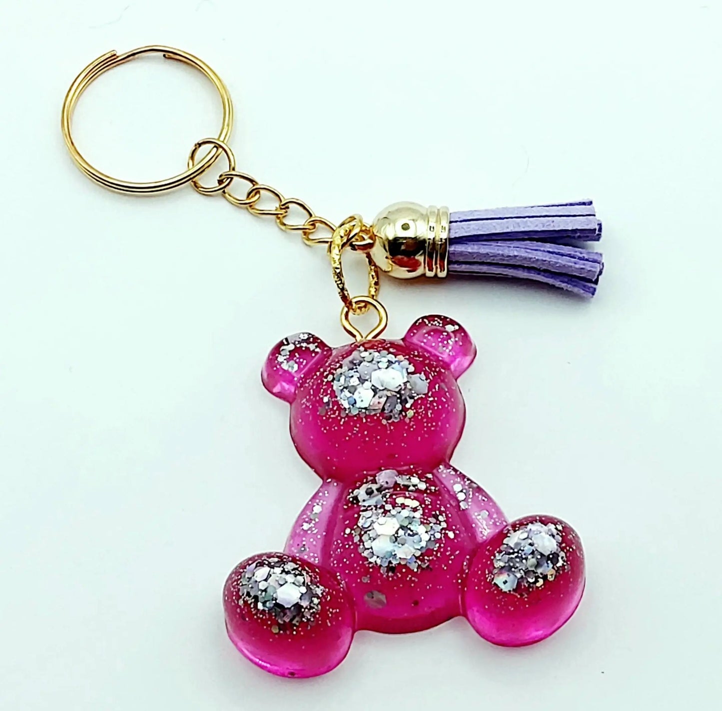 Porte-clés "Ourson assis" en résine époxy, rose et paillettes argentées. Anneau doré, pompon gland mauve.