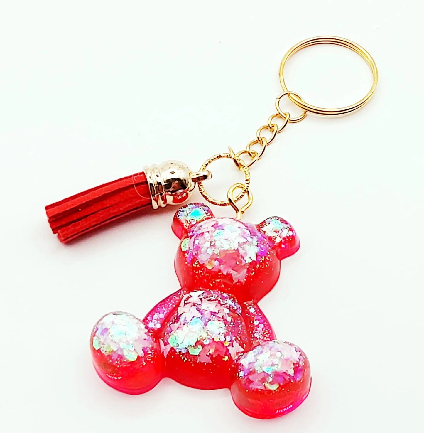 Porte-clés "Ourson assis" en résine époxy. Rouge translucide et paillettes papillons holographiques. Anneau doré. Pompon gland rouge.
