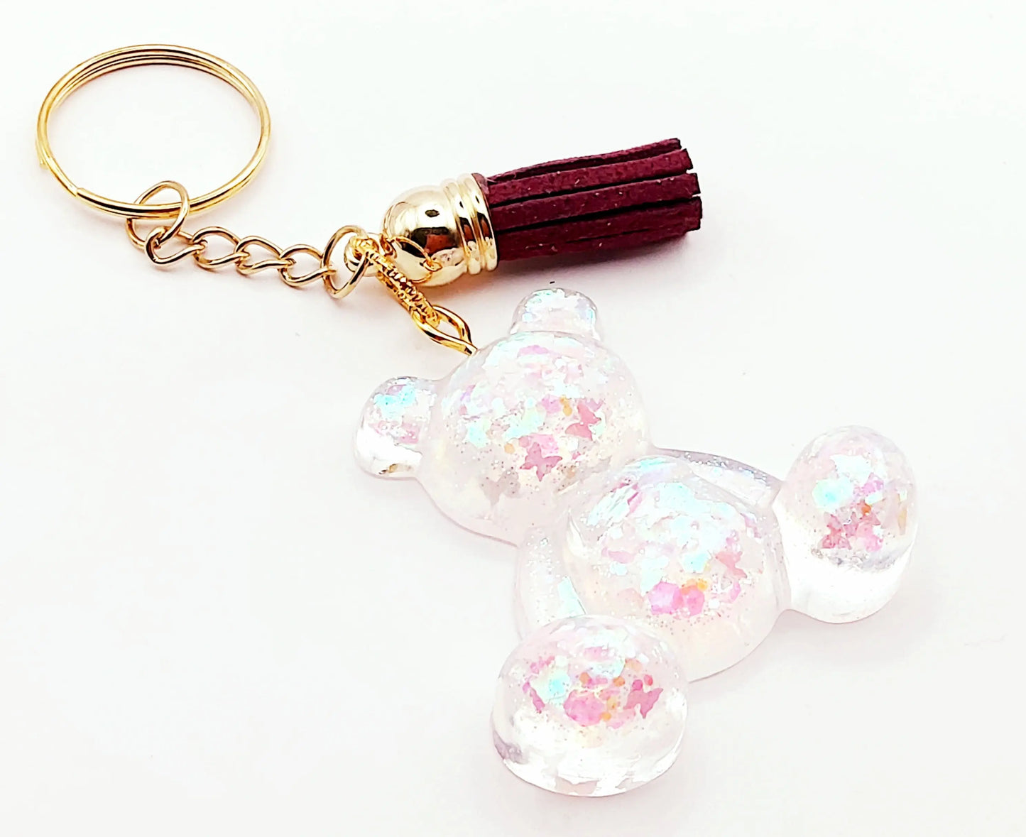 Porte-clés "Ourson assis" en résine époxy. Transparent et paillettes holographiques Papillons. Anneau doré. Pompon gland prune.