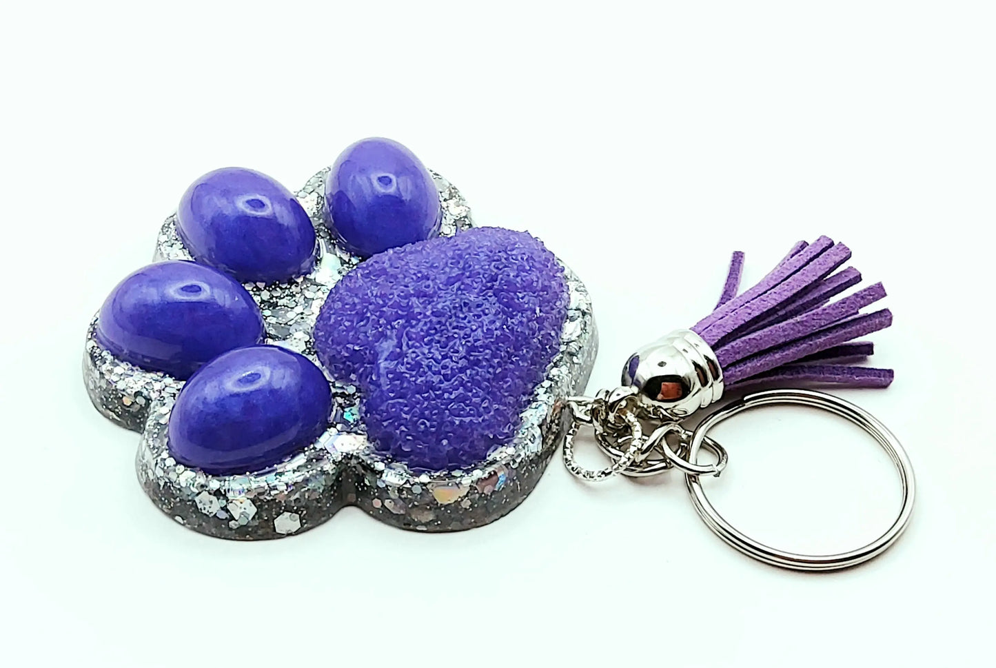 Porte-clés "Patte d'ours" en résine époxy. Violet et paillettes holographiques argentées. Anneau argenté, pompon gland violet.