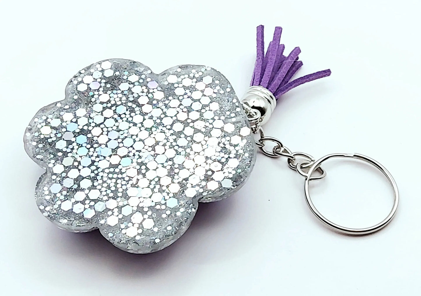 Porte-clés "Patte d'ours" en résine époxy. Violet et paillettes holographiques argentées. Anneau argenté, pompon gland violet. Vue de l'envers.