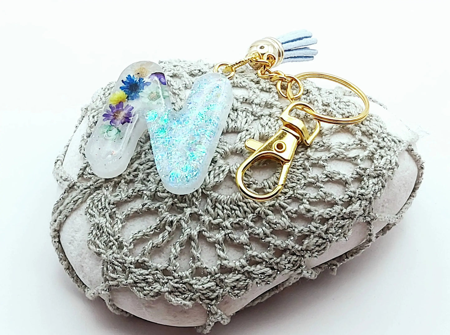 Porte-clés "Petite Lettre N" en résine époxy, fleurs multicolores, pompon gland bleu pastel, posé sur un galet
