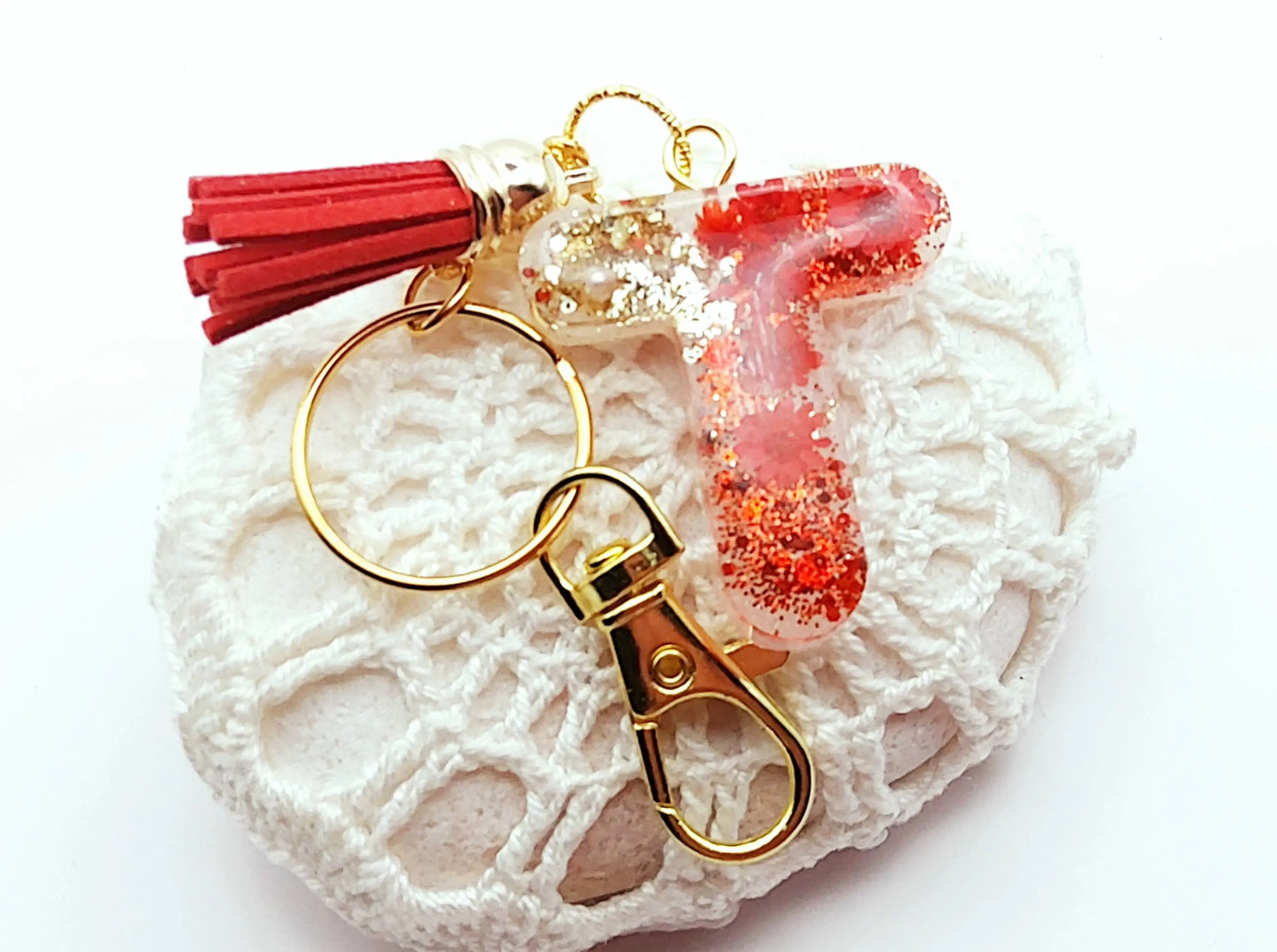 Porte-clés "Petite Lettre T" en résine époxy, fleurs et pompon gland rouges, posé sur un galet