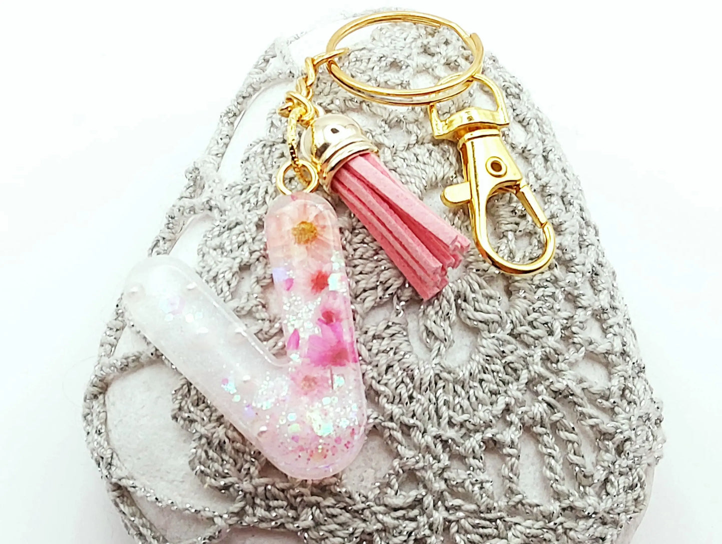 Porte-clés "Petite Lettre V" en résine époxy, fleurs et pompon gland roses, posé sur un galet