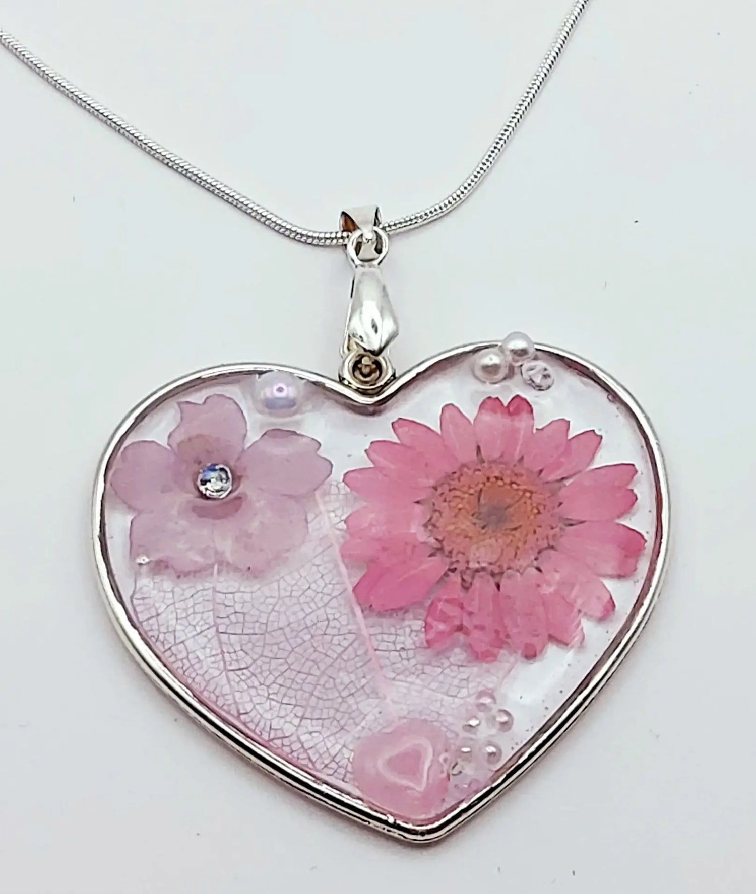 Pendentif Coeur argenté et sa chaîne en acier inoxydable. Fleurs roses et mauves