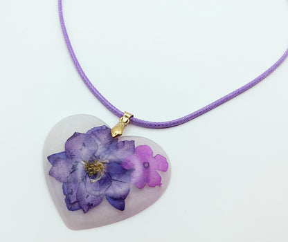 Pendentif Coeur fleuri en résine époxy. Blanc et fleurs séchées mauves. Cordon en coton ciré mauve