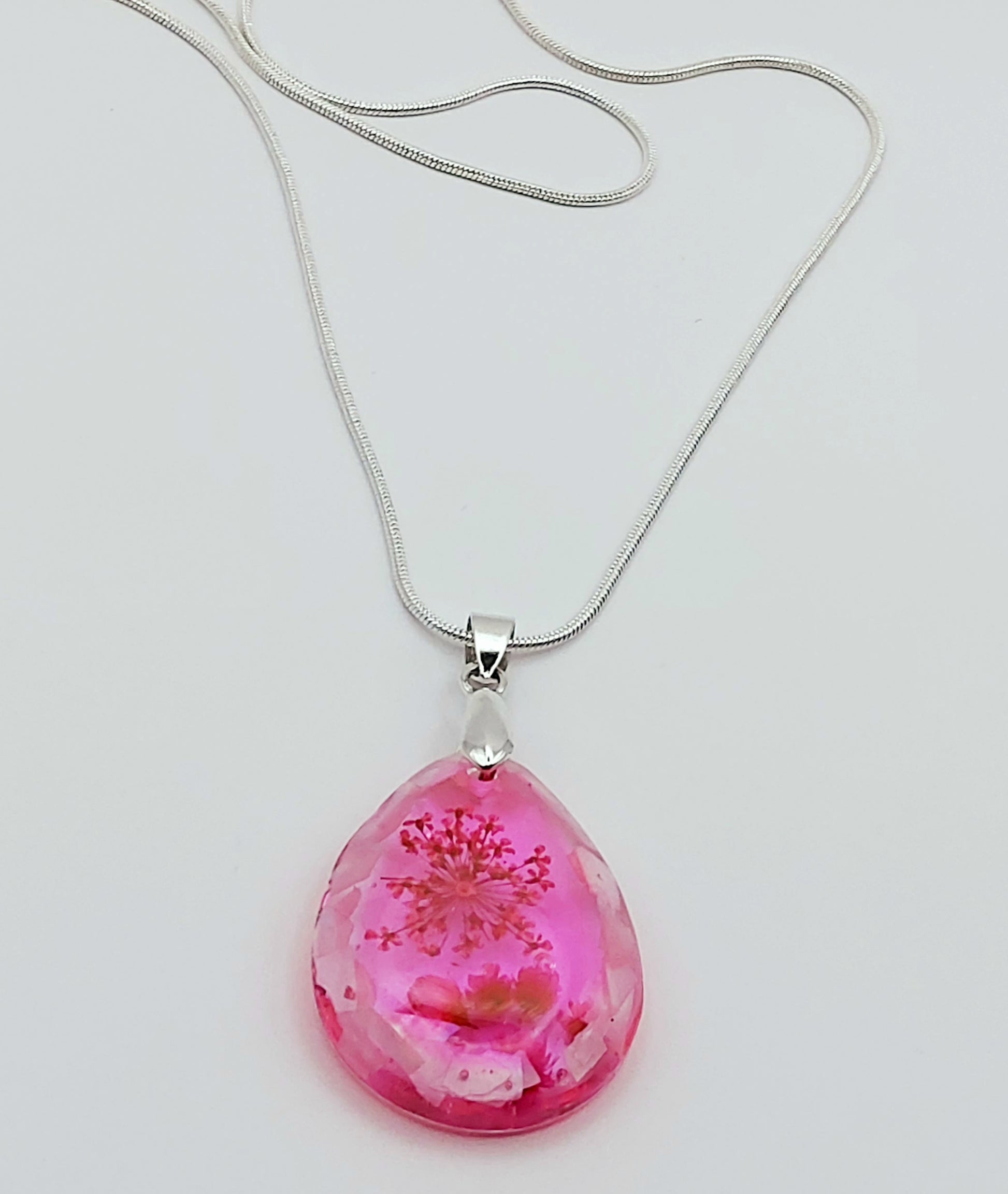 Pendentif "Goutte d'eau" en résine époxy et sa chaîne argentée. Fleurs et morceaux de coquillages roses.