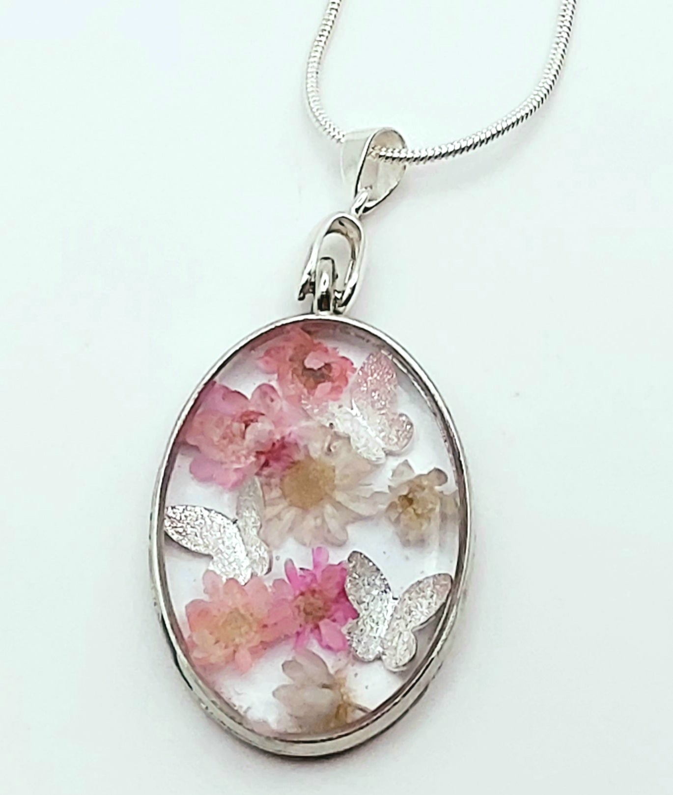 Pendentif Ovale orné de fleurs séchées roses et de papillons argentés - Gros plan - PRETTY RESINE