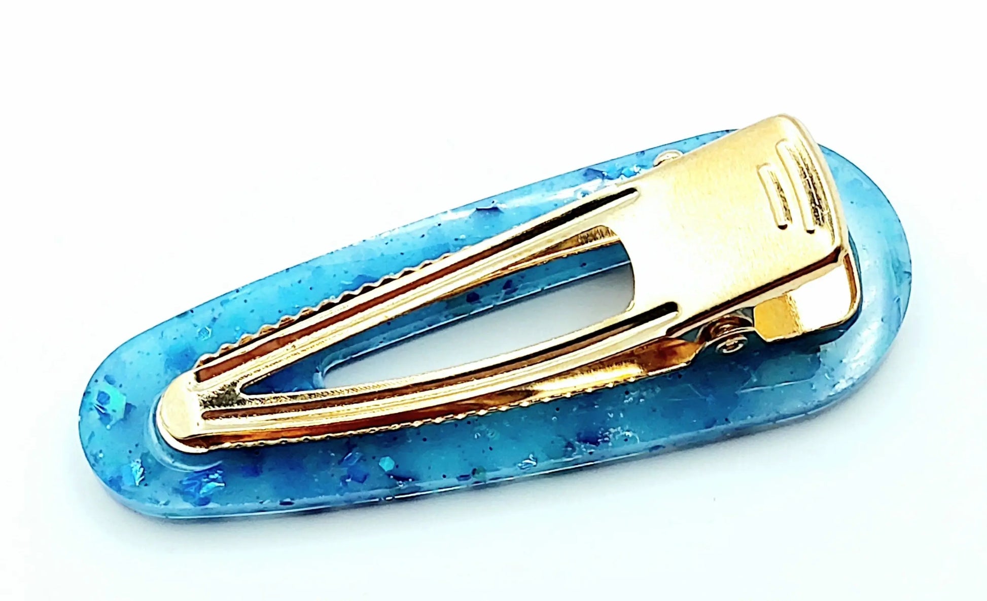 Barrette arrondie en résine époxy, bleu et paillettes holographiques. Vue du dessous.