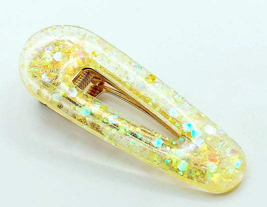 Barrette à cheveux arrondie en résine époxy. Jaune translucide et paillettes holographiques.