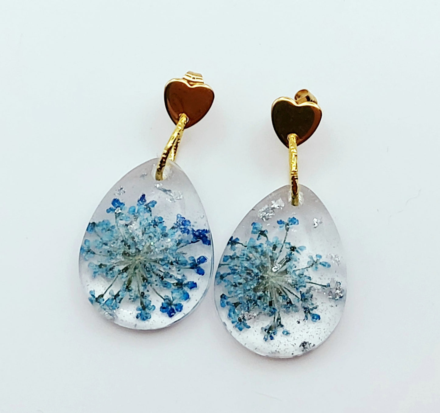 Boucles d'oreilles en résine "Fleur bleue dans une goutte d'eau", avec feuille d'argent, apprêts en forme de coeur, vue de face