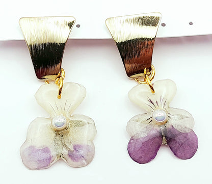 Boucles d'oreilles Fleurs de pensées en résine. Violet et blanc avec une perle blanche au centre. Apprêt doré.