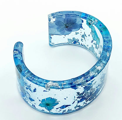 Bracelet manchette en résine époxy. Fleurs bleues et feuille d'argent.