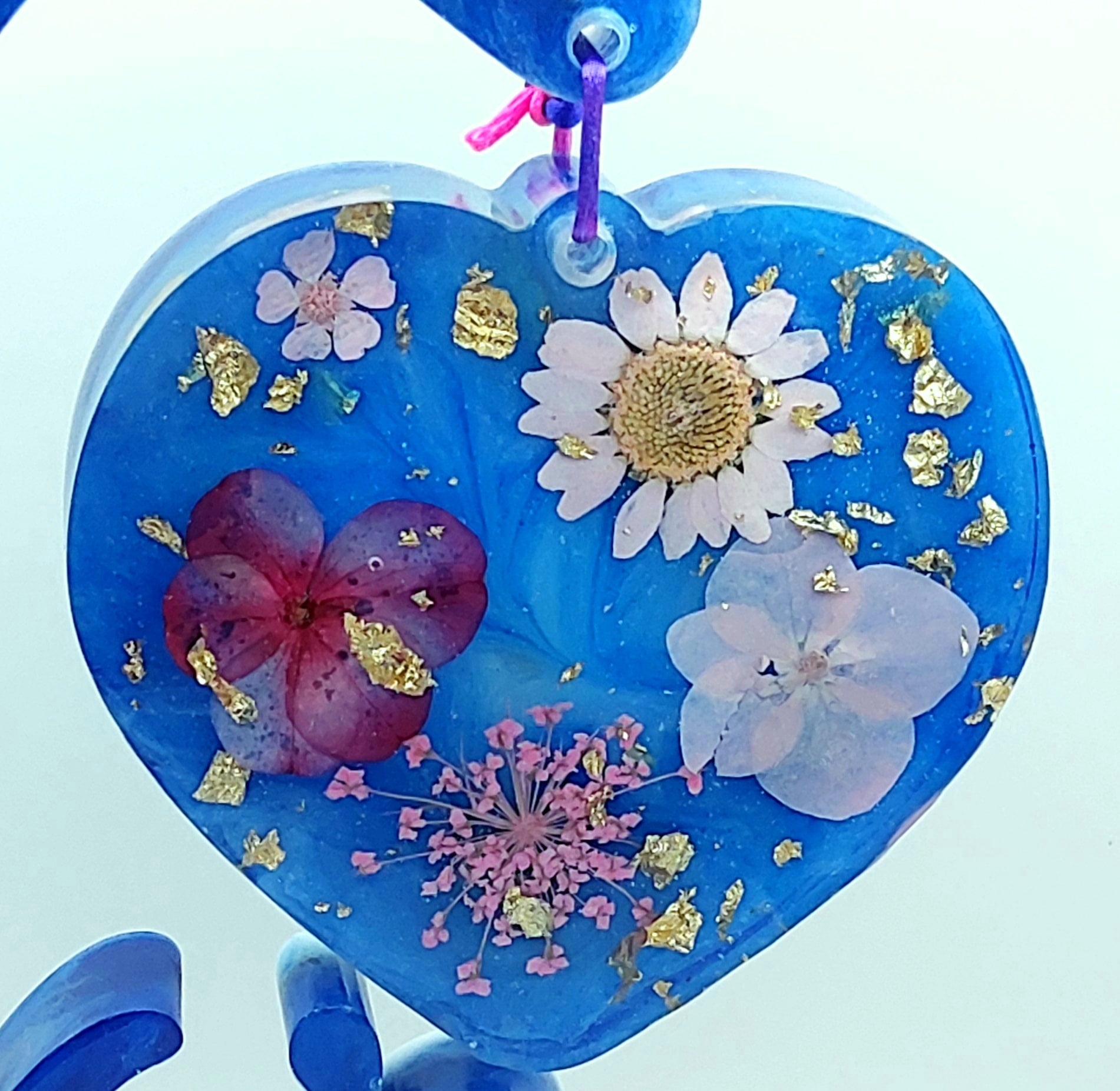 Gros plan sur le Coeur suspendu bleu et fleurs séchées roses