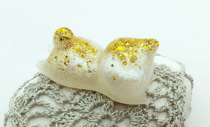 Figurine "Chaton couché" en résine époxy, blanc et paillettes dorées. Gros plan.