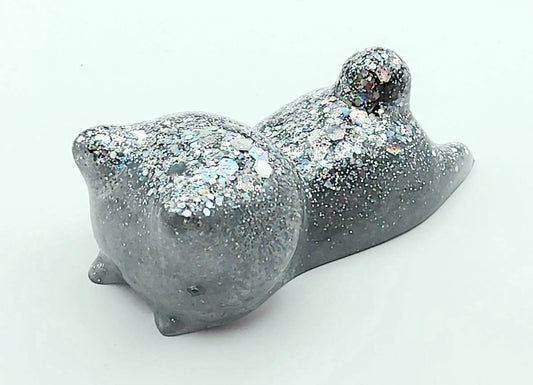 Figurine Chaton couché en résine époxy, gris et paillettes holographiques. Gros plan.