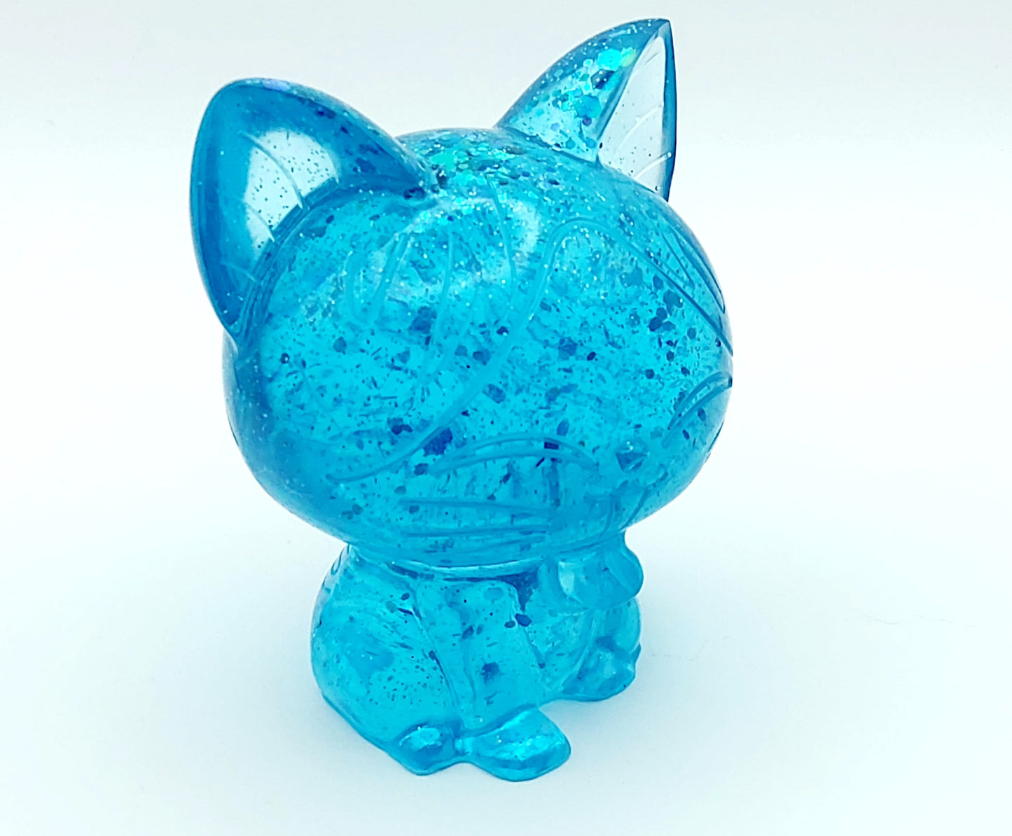 Figurine Chat Kawaii en résine époxy, turquoise translucide et paillettes. Gros plan.