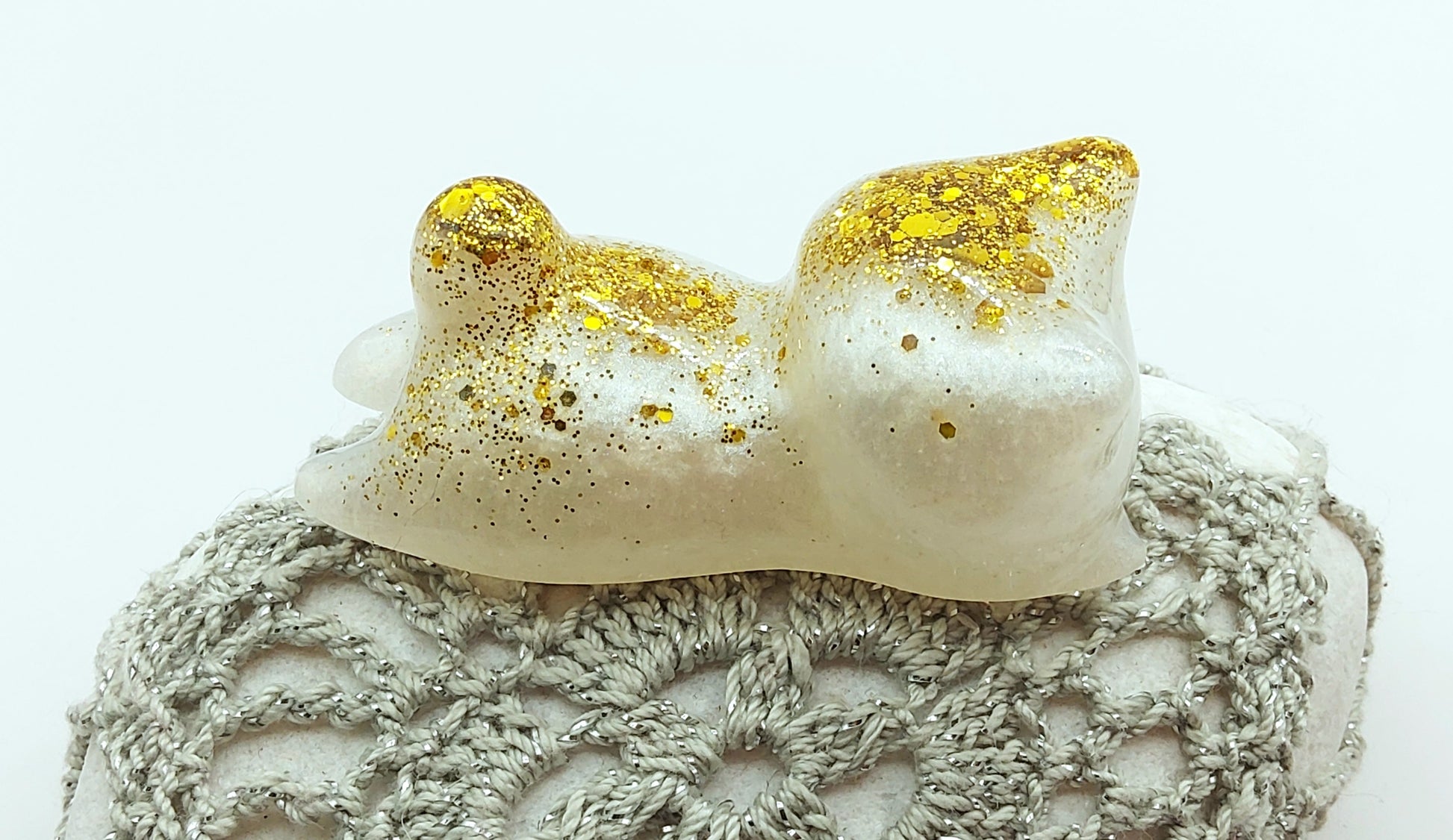 Figurine "Chaton couché" en résine époxy, blanc et paillettes dorées. Gros plan.