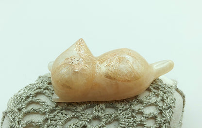 Figurine "Chaton couché" en résine époxy, beige nacré, posé sur un galet.