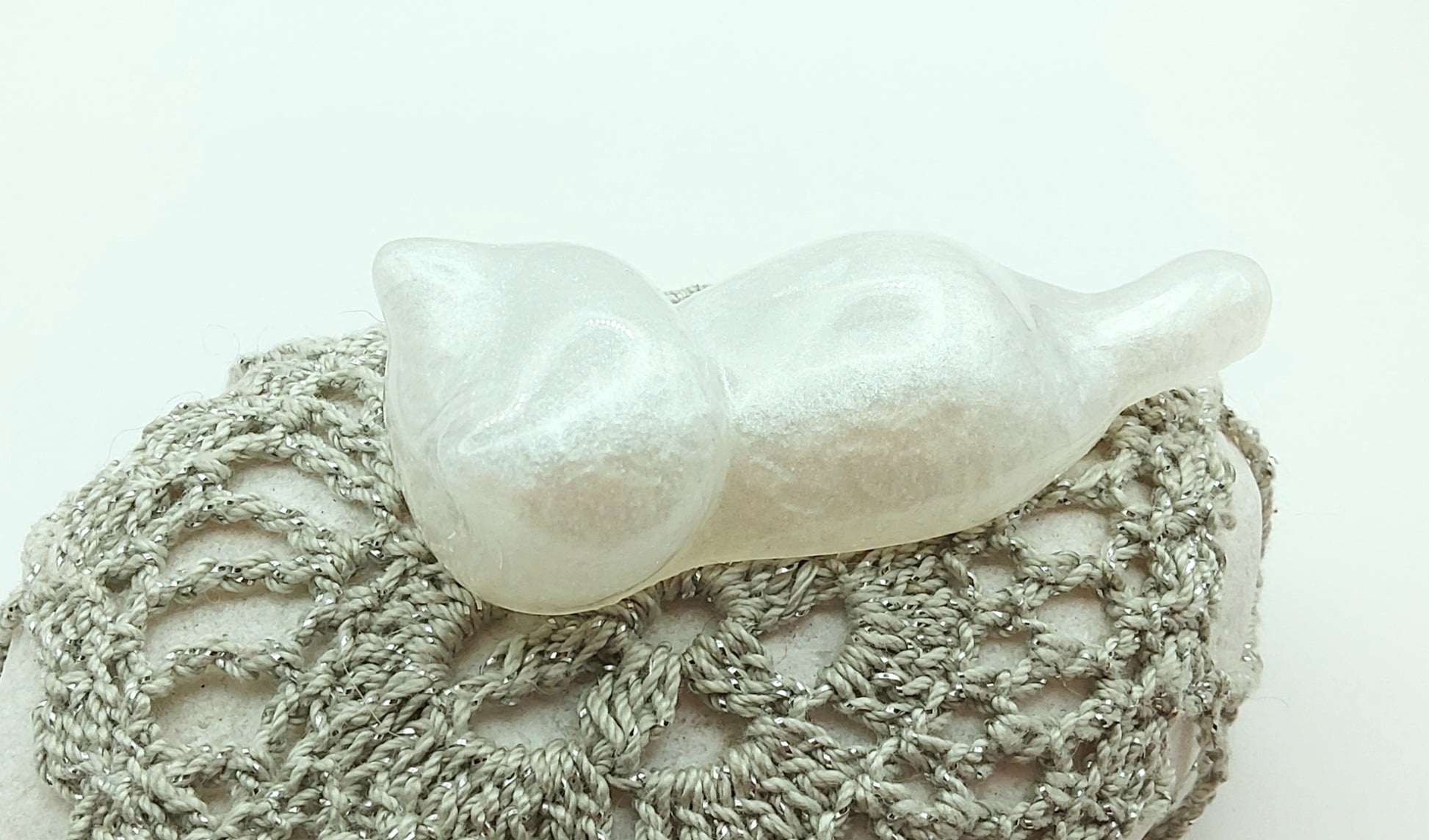 Figurine "Chaton couché" en résine époxy, blanc nacré. Posé sur un galet.