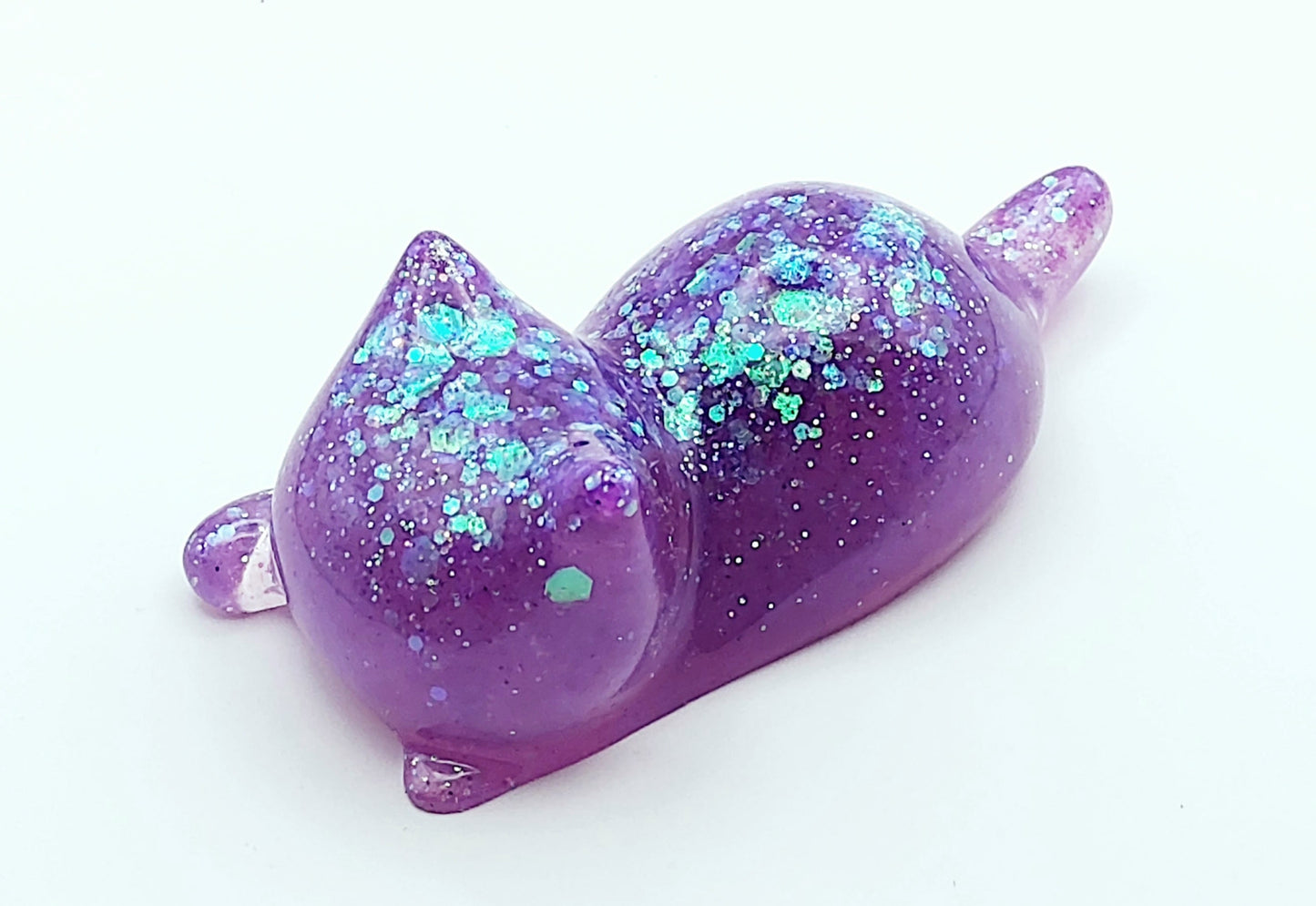 Figurine "Chaton couché" en résine époxy, mauve et paillettes holographiques.