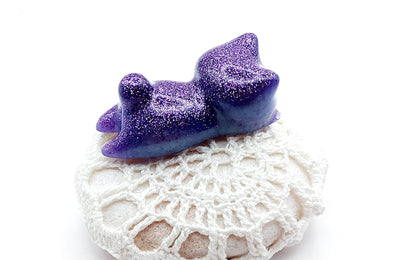 Figurine "Chaton couché" en résine époxy, violet et paillettes, posé sur un galet