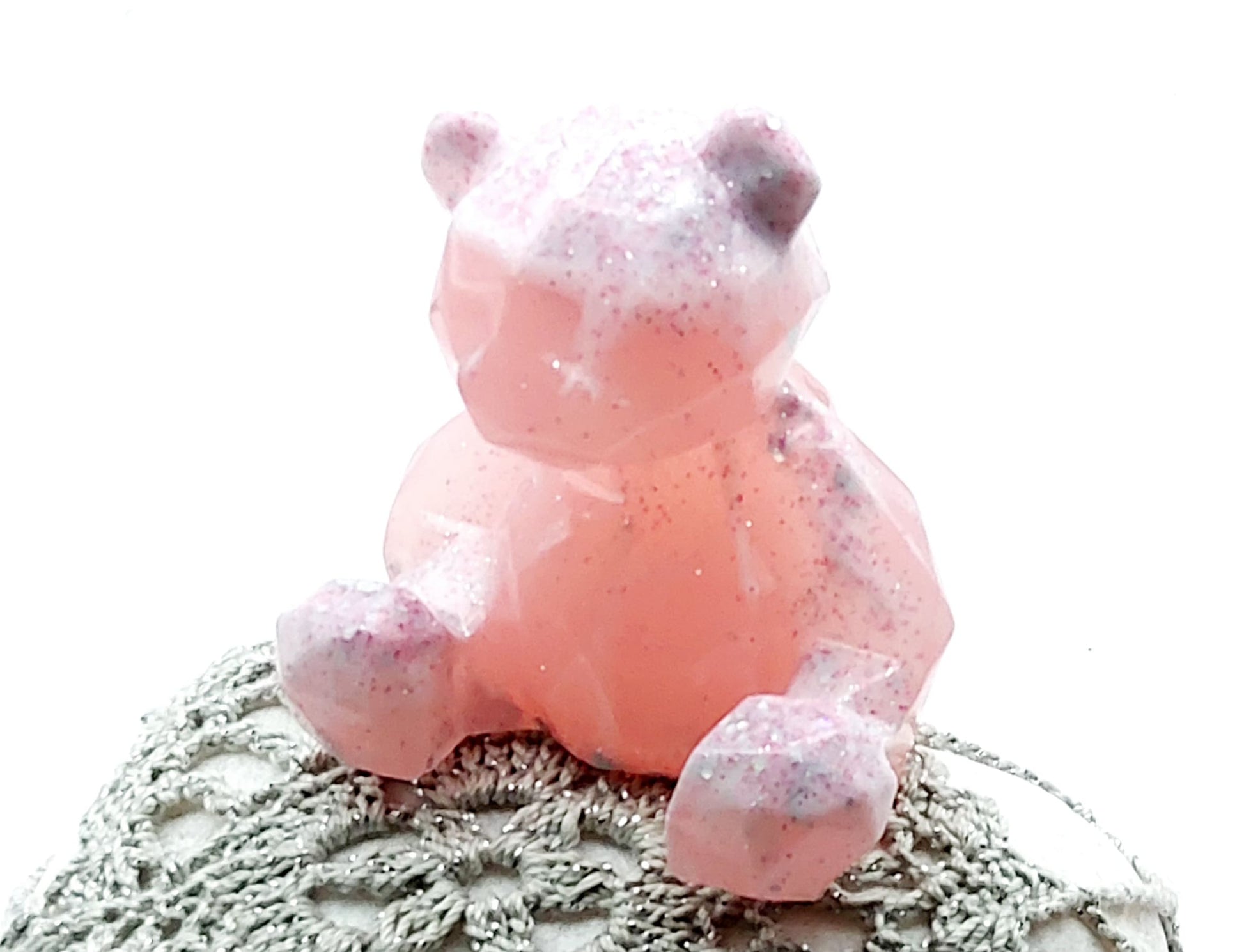 Figurine "Ourson assis" en résine époxy. Rose pastel avec paillettes roses et argentées. Posé sur un galet.