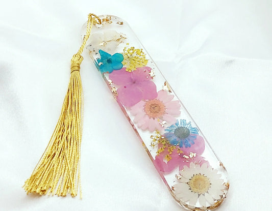 Marque-pages en résine époxy. Transparent avec fleurs séchées multicolores, feuille d'or, et pompon gland soyeux doré.