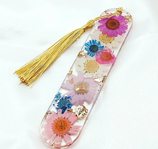 Marque-pages en résine époxy. Transparent avec fleurs multicolores et feuille d'or. Pompon gland soyeux doré.